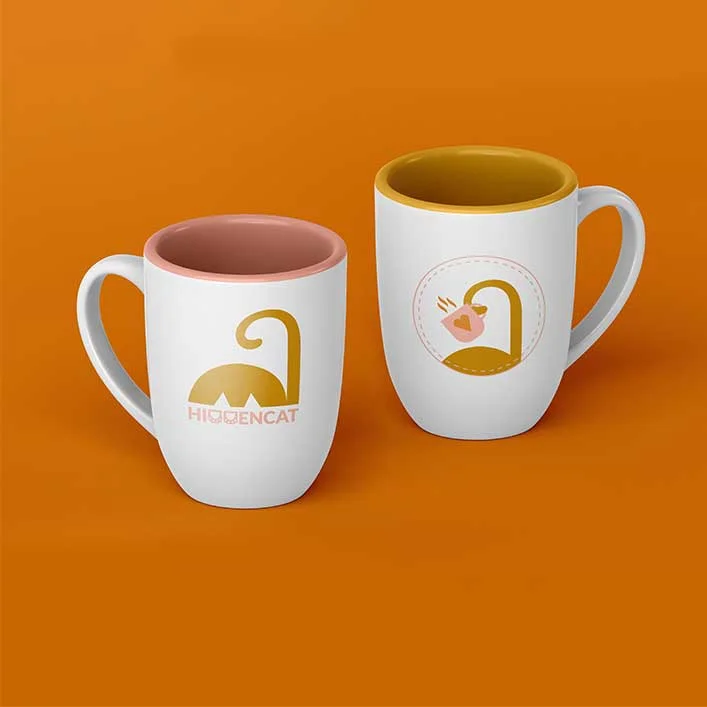 Zwei Tassen mit Katzenlogo auf orangenem Hintergrund