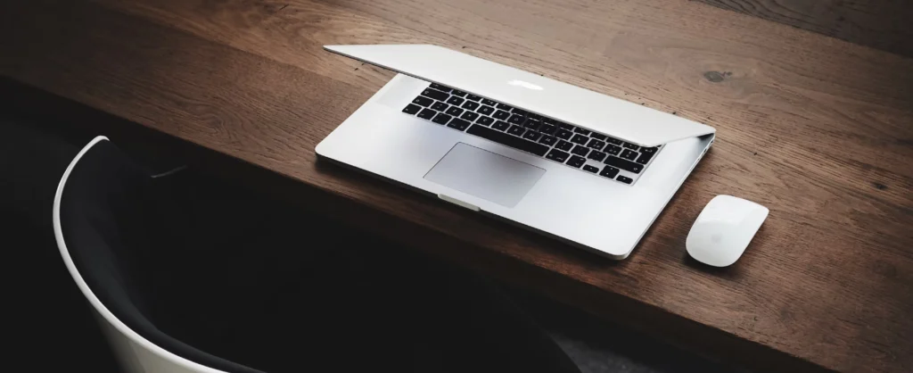 freelancer vs. agentur: die richtige wahl für dein projekt als Text und dahinter ein Bild von einem leicht aufgeklappten weißen Laptop von Apple